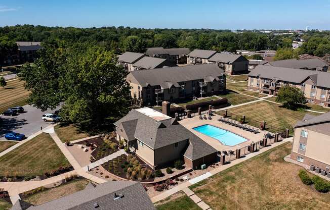 An aerial view of Olde English Village Apartments, nestled among the serene landscape, featuring a cluster of well-maintained buildings with courtyards and walkways.