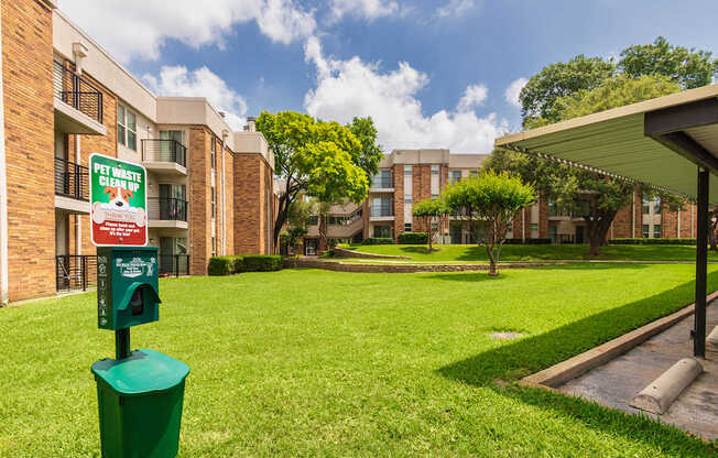 A green trash can is in front of a sign that says Pet Waste Cleanup.