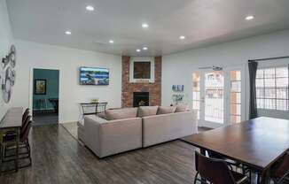 A living room with a couch, chairs, and a flat screen TV mounted on the wall.