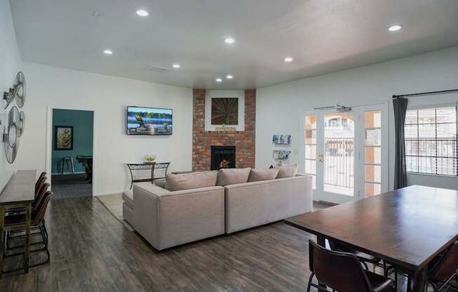 A living room with a couch, chairs, and a flat screen TV mounted on the wall.