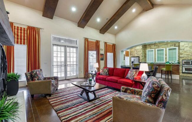 Clubhouse Interior with red and orange accents, a red sofa, orange curtains, two accent chairs, and a striped rug