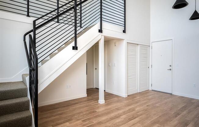 a living room with a staircase in a house with white walls and wood floors