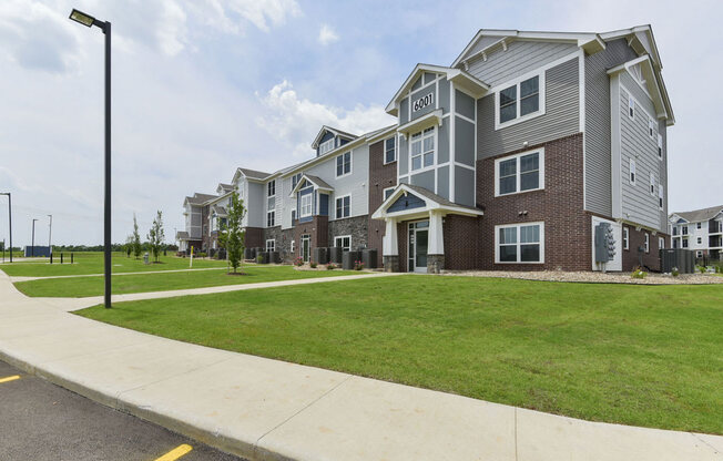 the outlook of a row of apartment buildings with green grass and sidewalks at Dodson Pointe Apartment Homes, Rogers, AR, 72758