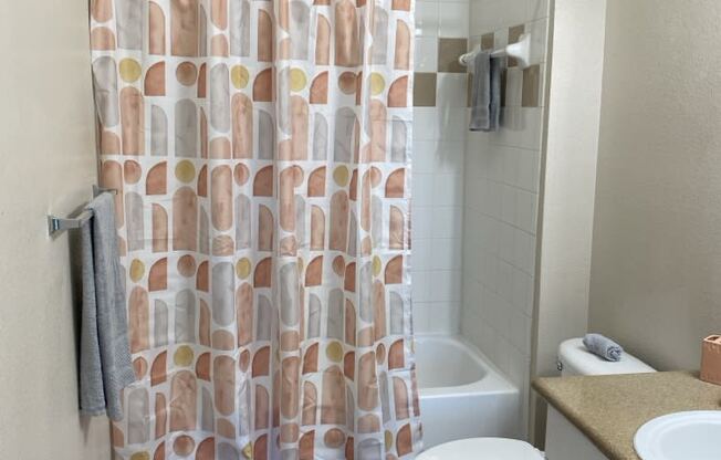 a bathroom with a shower curtain and a toilet and a sink