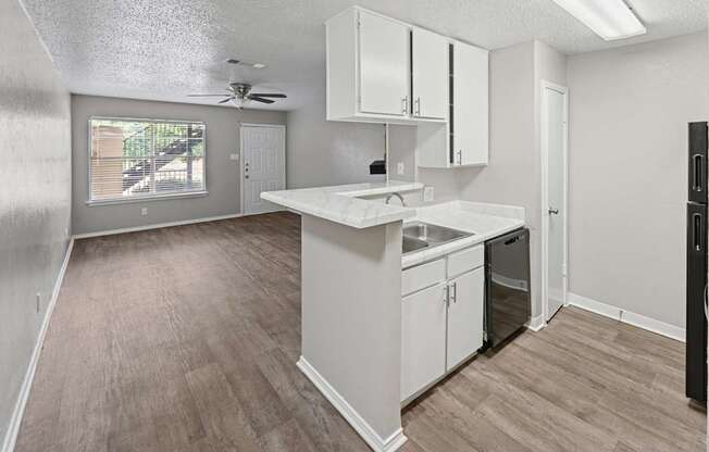 A kitchen with white cabinets and a wooden floor.