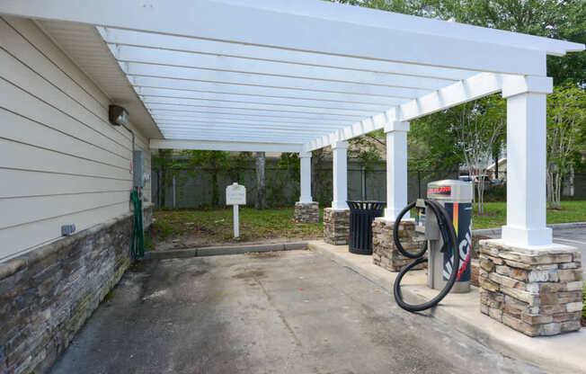 A gas station with a white canopy and a green hose.