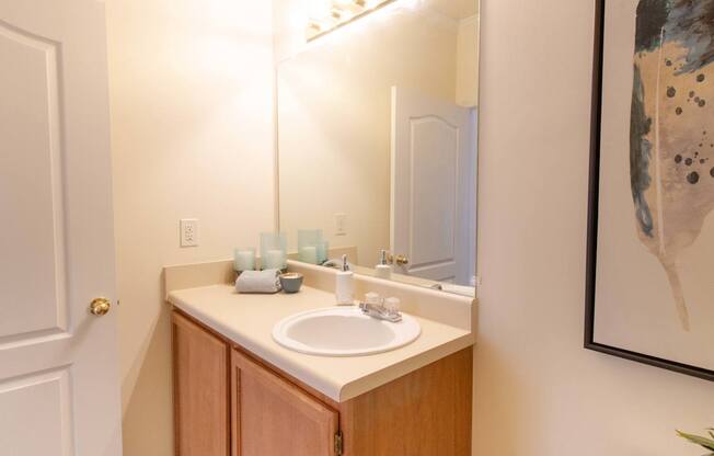 A bathroom with a sink, mirror, and a painting on the wall.