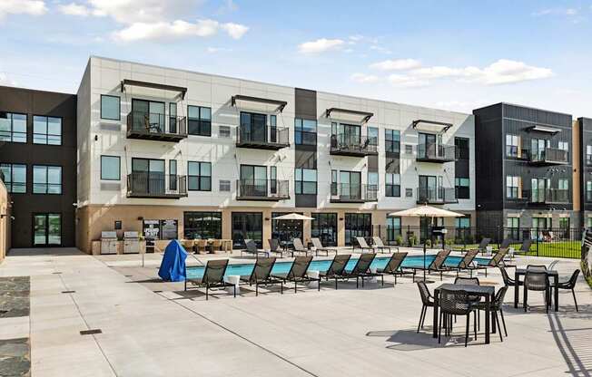 A modern building with a pool and lounge chairs.