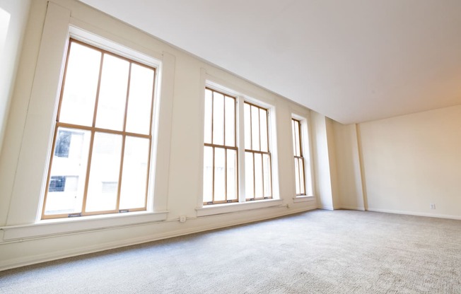 an empty living room with three large windows at 26 West, Managed by Buckingham Urban Living, Indianapolis