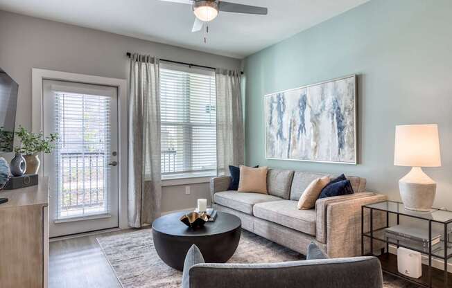 A living room with a grey couch, a coffee table, and a painting on the wall.