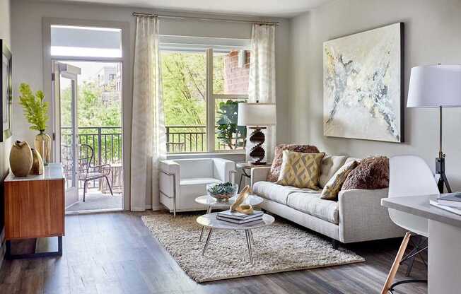 A living room with a white couch and a painting on the wall.
