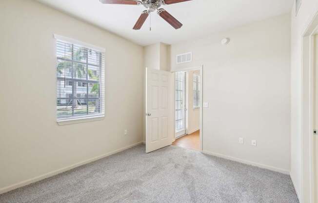 A room with a ceiling fan and a window with blinds.