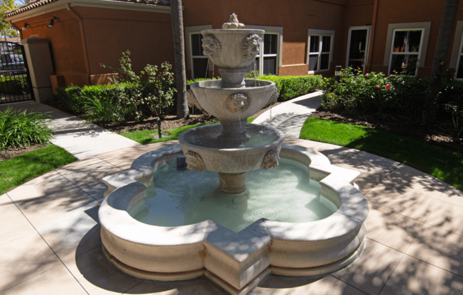 A stone fountain with three tiers of water jets out of a basin.