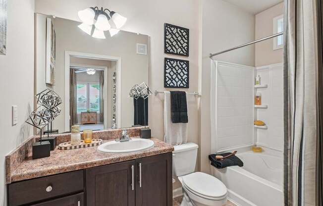 A bathroom with a brown granite countertop and white fixtures.
