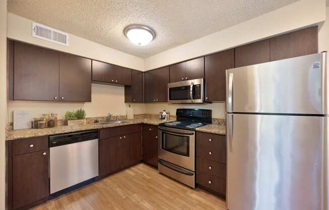 full kitchen with stainless steel appliances and wood flooring in an apartment