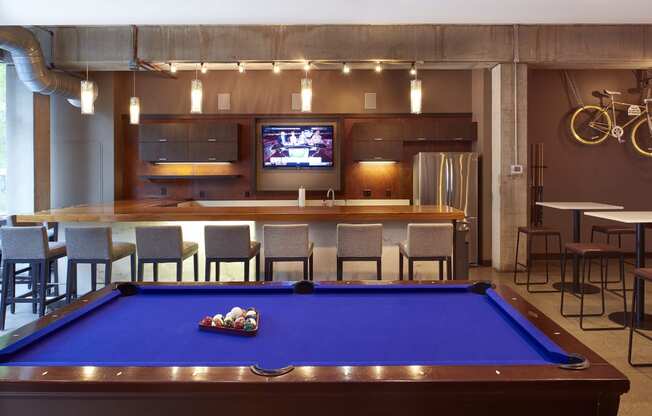 a pool table in a room with a bar and a tv