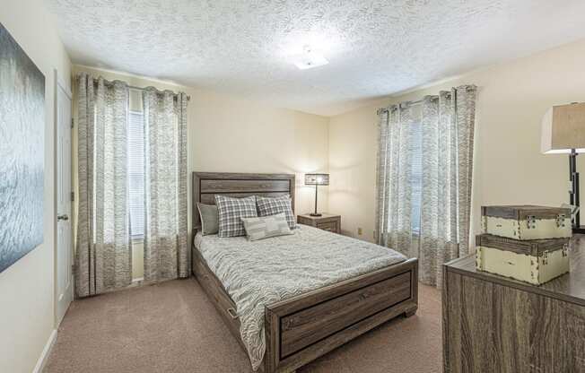 a bedroom with a bed and windows with curtains