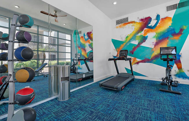 a gym with cardio equipment and a painting on the wall