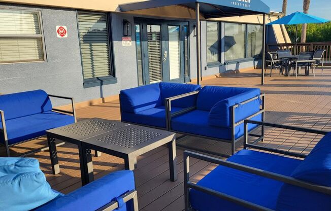 A patio with blue cushioned chairs and a table.