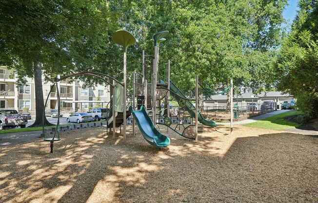A playground with a green slide and a brown ground.