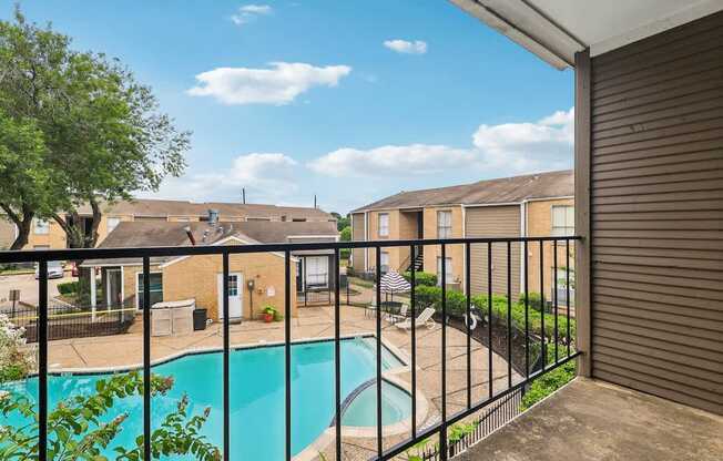 A pool in a backyard with a fence and houses in the background.