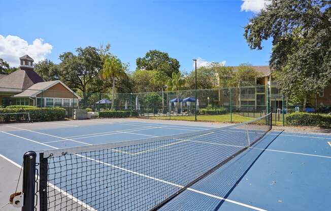 A tennis court with a black net and a building in the background.