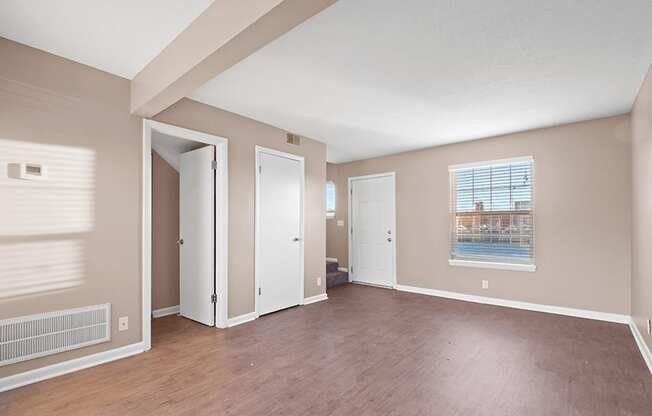 an empty living room with wood flooring and a window