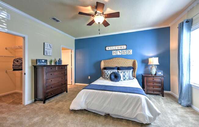 A bedroom with a bed, dresser, and ceiling fan.