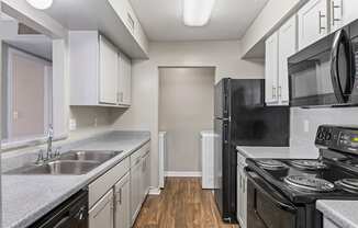A kitchen with black appliances and white cabinets.