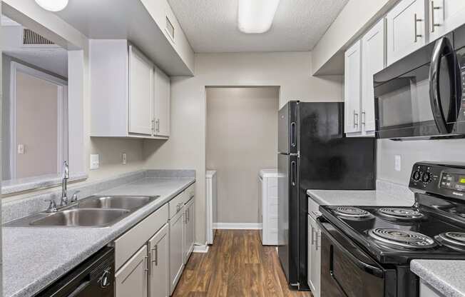 A kitchen with black appliances and white cabinets.