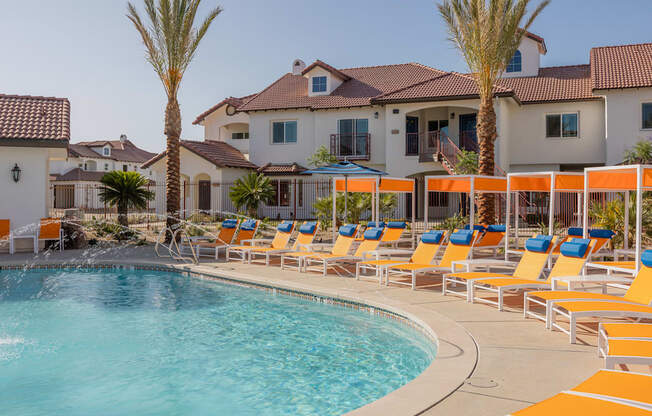 A pool with chairs and palm trees in front of a house.