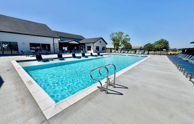 A large outdoor swimming pool with a diving board and lounge chairs.