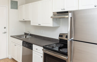A kitchen with white cabinets and a black fridge.