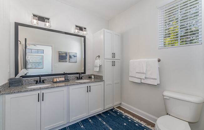 a bathroom with white cabinets and a blue rug