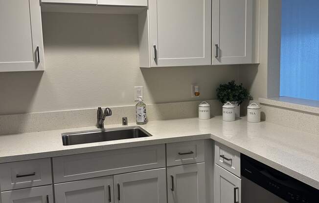 an empty kitchen with white cabinets and a sink