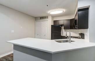 an empty kitchen with a sink and a refrigerator at Ashford Belmar Apartments, Colorado