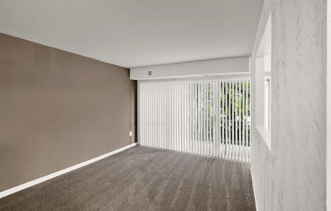 an empty living room with white blinds and a window