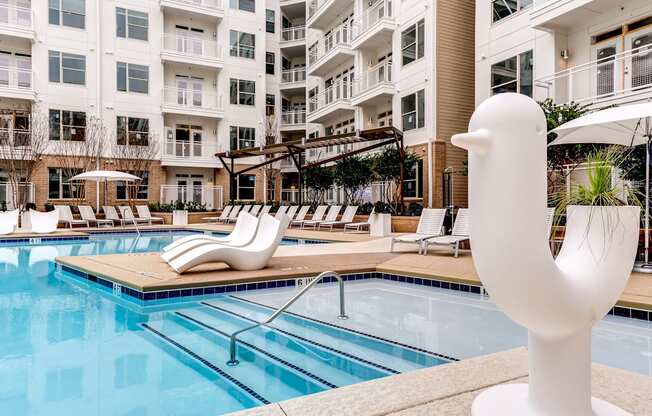 a swimming pool with a white duck statue in front of an apartment building