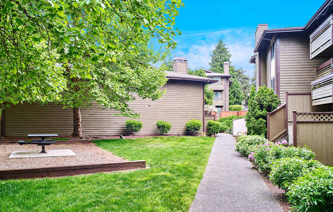 A backyard with a picnic table and a concrete path at apartments in Renton, WA.