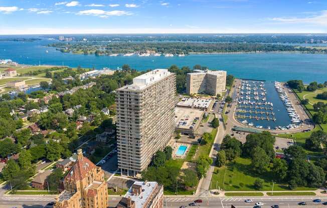 Exterior of the Jefferson. The building is on the Detroit River. There is green grass around the building. The Jefferson stands 30 stories tall. The sun is shining and there are blue skies.