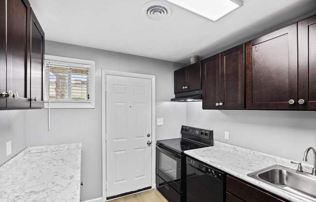 A kitchen with dark wood cabinets and a black stove top oven.