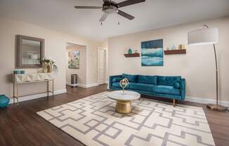 A living room with a blue couch and a patterned rug.