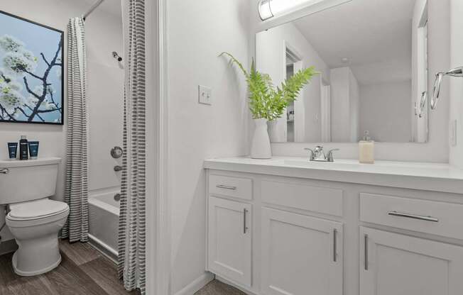 A white bathroom with a toilet, sink, and a window.