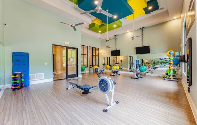 A gym with a variety of equipment including a weight bench, a rowing machine, and a treadmill.