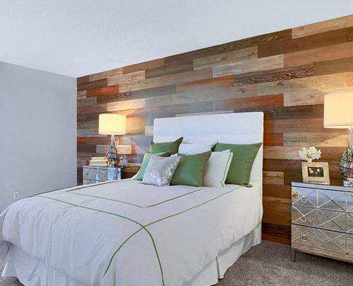 A bedroom with a white bed and a wooden wall.