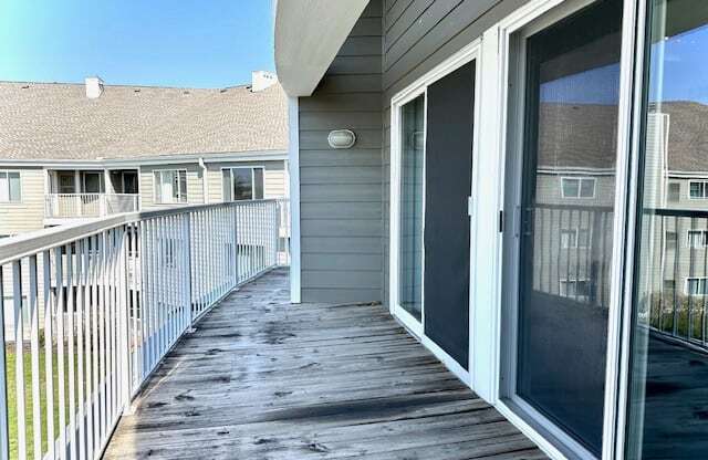 a porch with a glass door and a house in the background