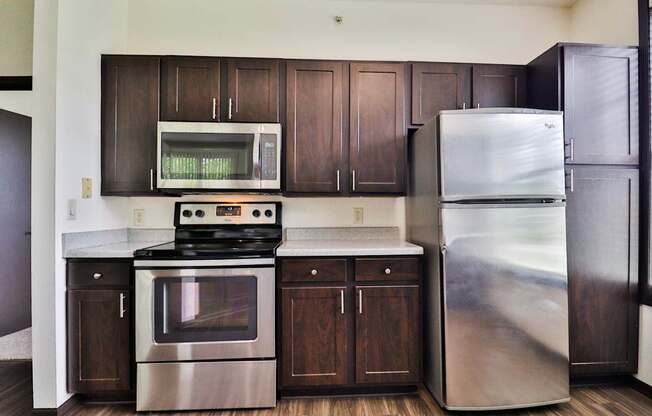 A modern kitchen with dark wood cabinets and stainless steel appliances.