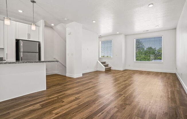 an empty living room and kitchen with wood floors and a refrigerator  at Aero Luxury Townhomes in Layton, Utah