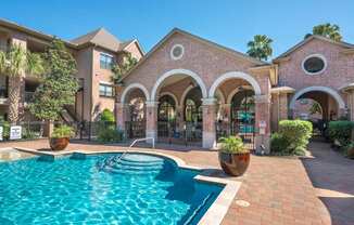 A pool in a courtyard surrounded by a building with arches.