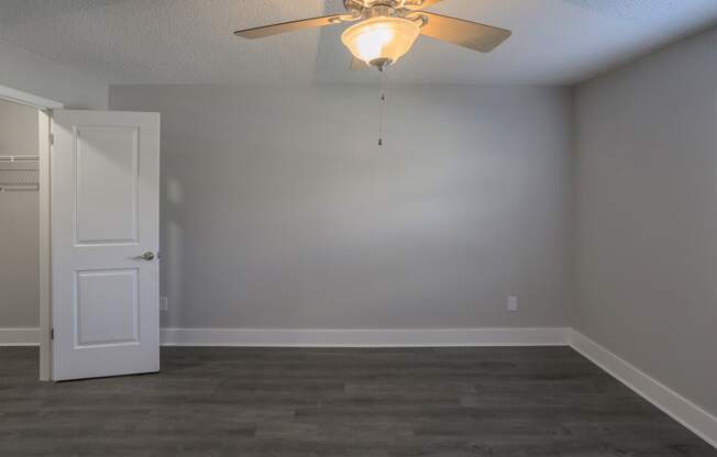 an empty living room with a ceiling fan and a white door